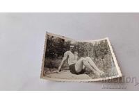 Φωτογραφία Νέος άνδρας με κοντό παντελόνι να κάθεται σε βράχο