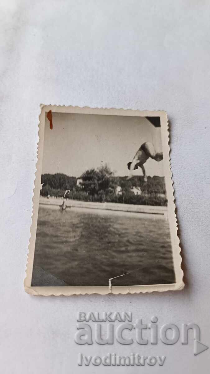 Photo: Young man jumping into a swimming pool