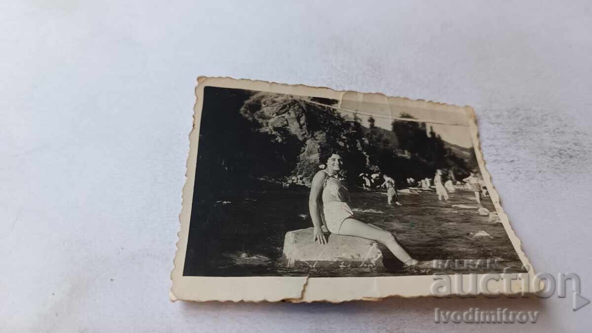 Photo of a young girl sitting on a rock in the river Photo of a young girl sitting on a rock in the river