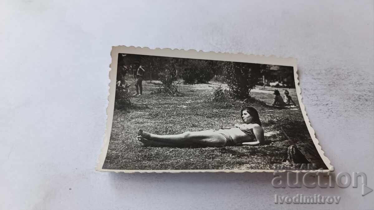 Снимка Младо момиче с ретро бански легнало на тревата