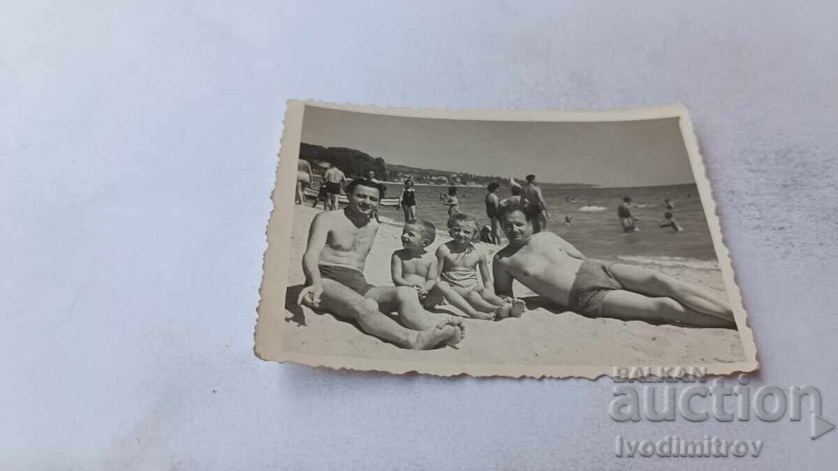 Fotografie: Doi bărbați cu doi băieți mici pe plajă