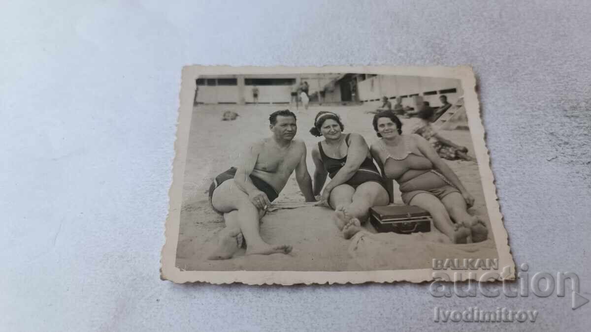 Fotografie cu un bărbat și două femei pe plajă Fotografie cu un bărbat și două femei pe plajă