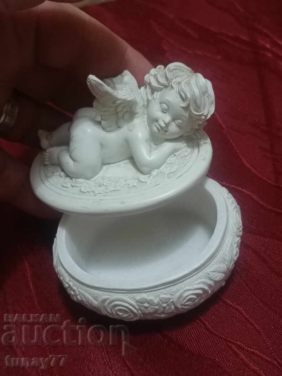 Delivery of Jewelry seated angel with a small bouquet in raised right hand