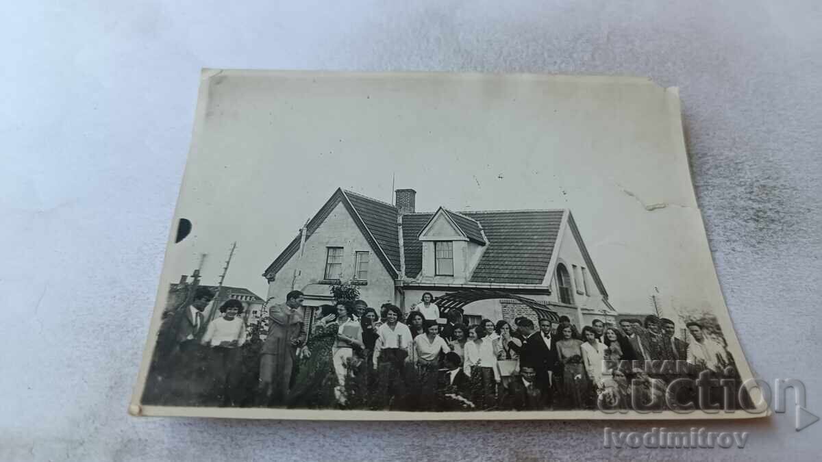 Φωτογραφία Άνδρες και γυναίκες μπροστά από μονοκατοικία Φωτογραφία Άνδρες και γυναίκες μπροστά από μονοκατοικία