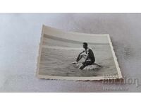 Photo: Young man sitting on a rock in the sea