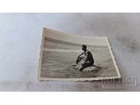 Photo: Young man sitting on a rock in the sea