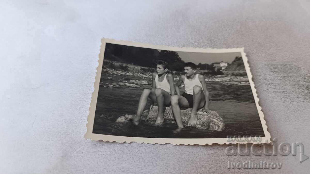 Снимка Две момчета седнали на скала в морето