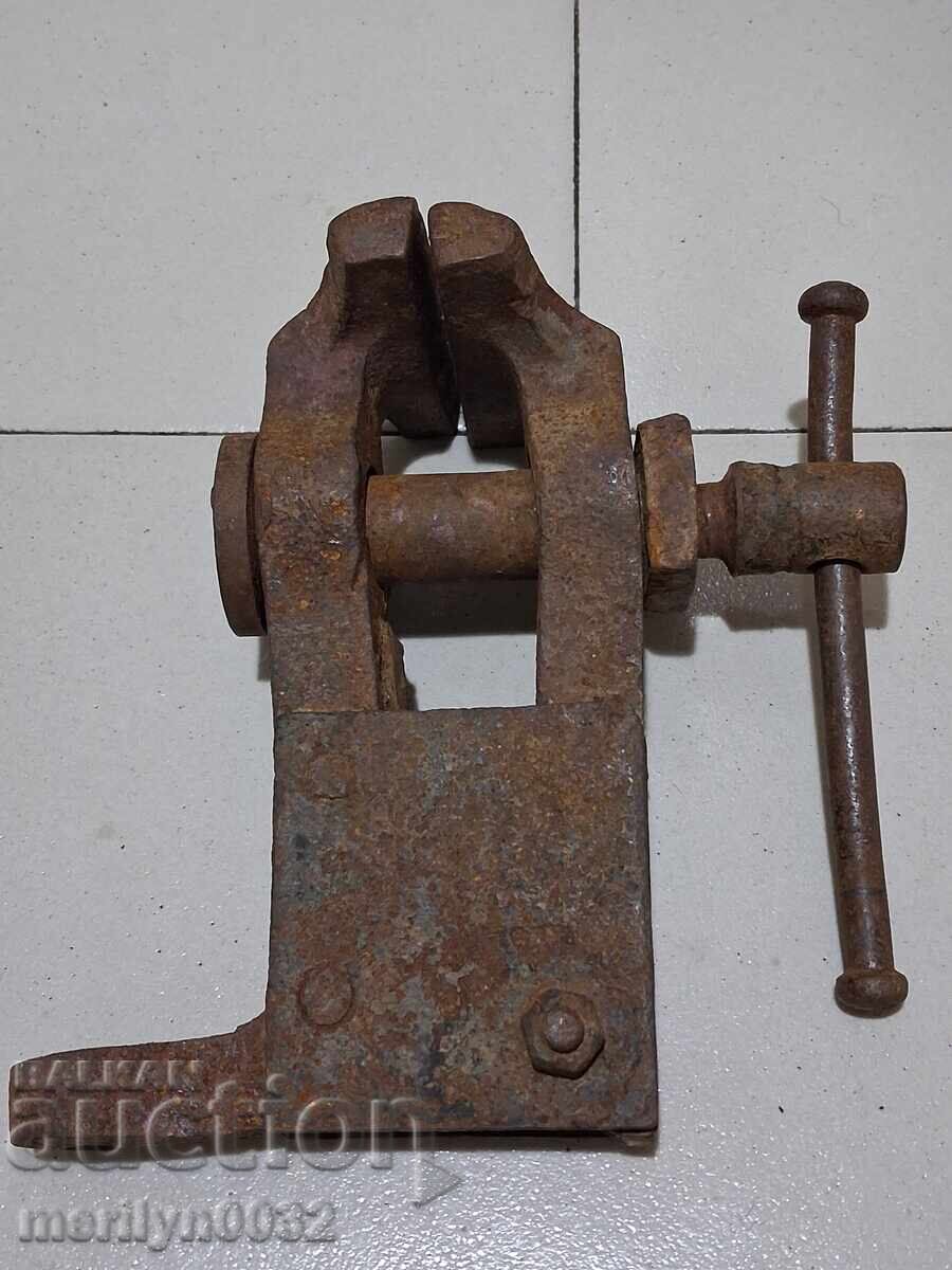 An old vise clamps a blacksmith's tool