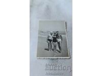 Photo of two young men and a young woman on the beach