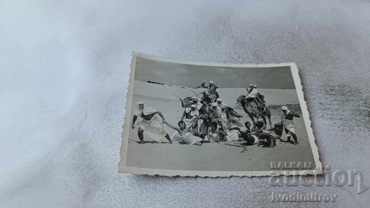 Φωτογραφία Νέων και κοριτσιών με δύο καμήλες στην παραλία