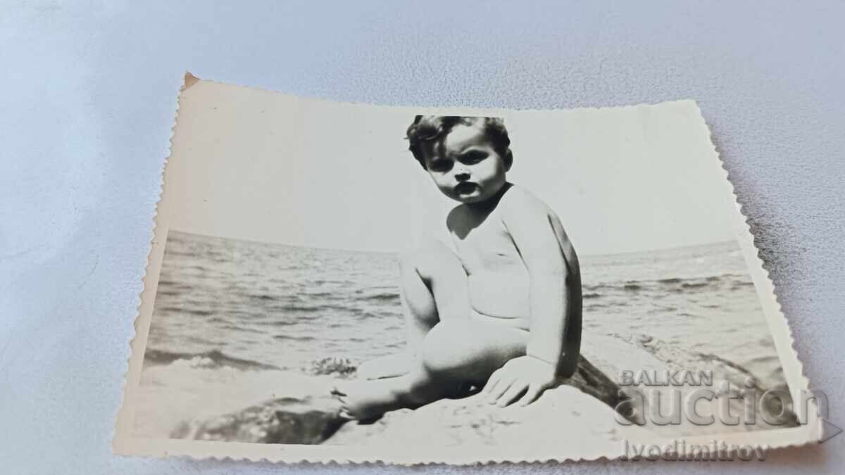 Picture of a little boy sitting on a rock by the sea