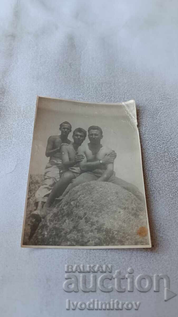 Φωτογραφία Τριών νέων που κάθονται σε βράχο