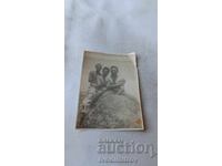 Fotografie cu trei tineri șezând pe o stâncă