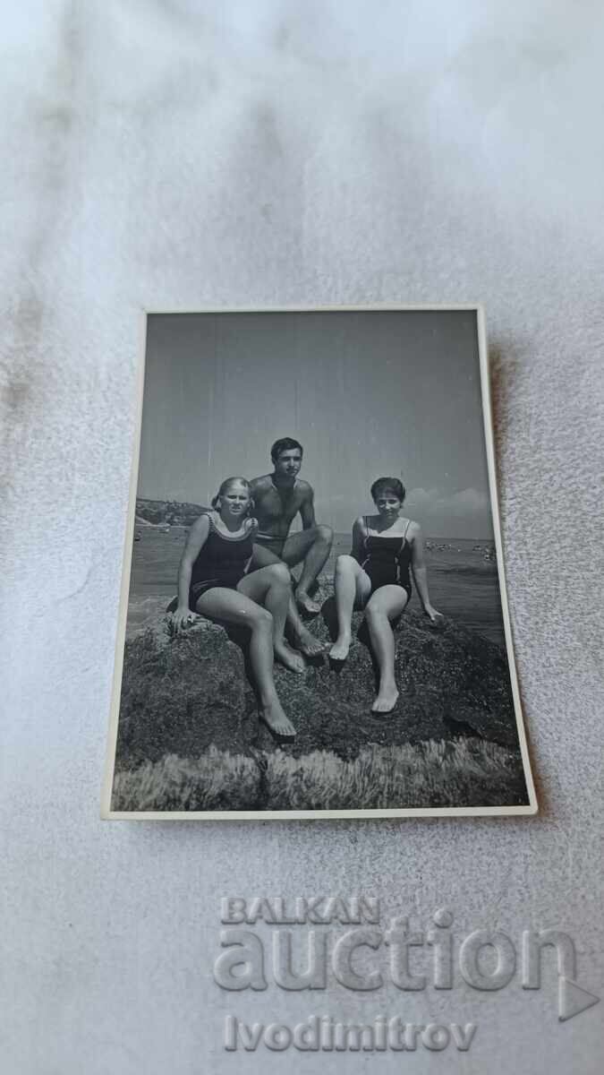 Φωτογραφία Άνδρας γυναίκα και νεαρό κορίτσι κάθονται σε βράχο πάνω από τη θάλασσα