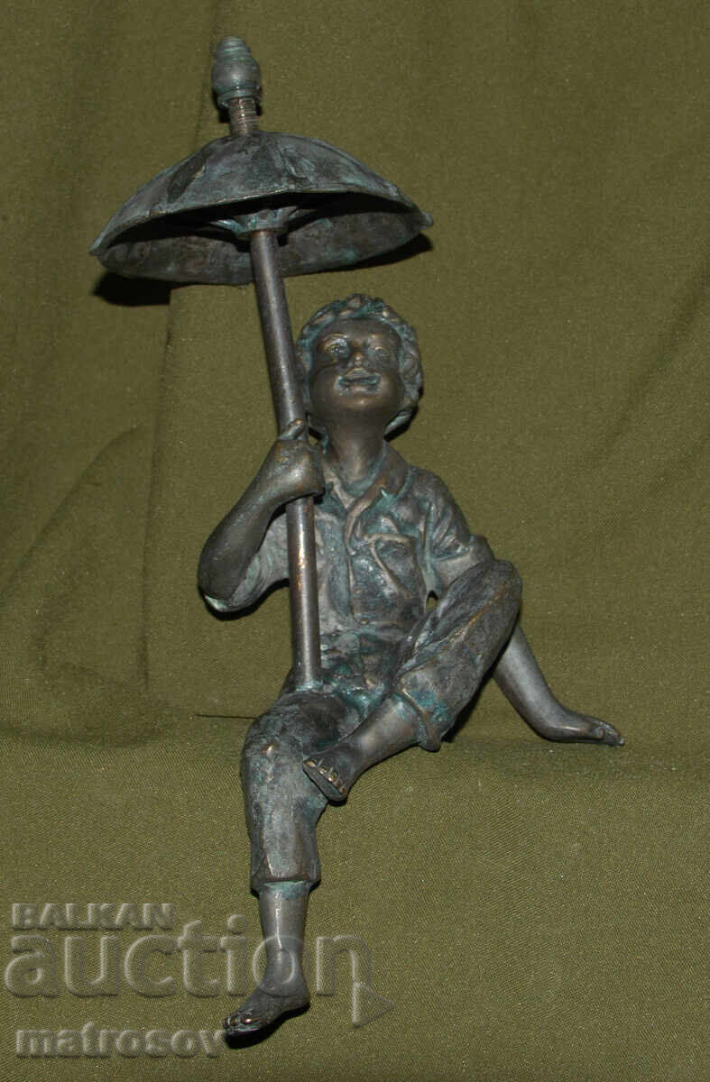 Old bronze sculpture of a boy with an umbrella