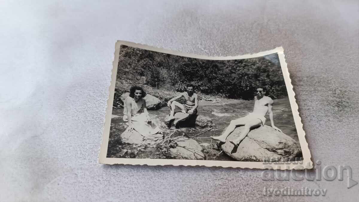 Φωτογραφία Δύο άνδρες και κοπέλα κάθονται σε πέτρες στο ποτάμι Φωτογραφία Δύο άνδρες και κοπέλα κάθονται σε πέτρες στο ποτάμι