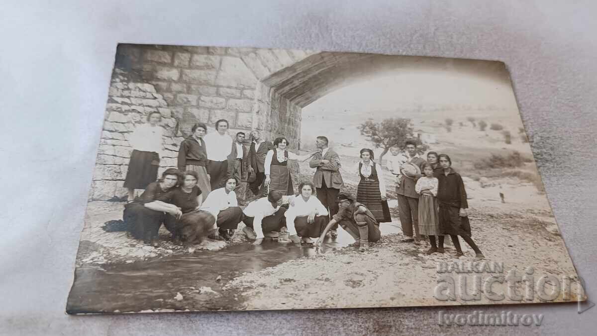 Photo of Young Men and Women Under a Bridge on a River