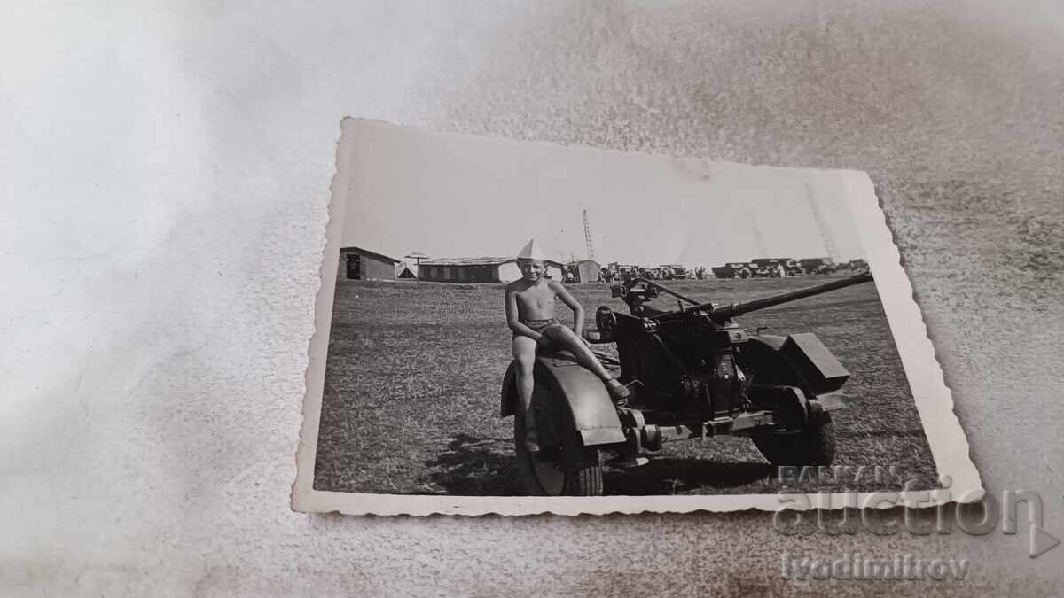 Photo of a Boy Sitting on a Cannon Tire