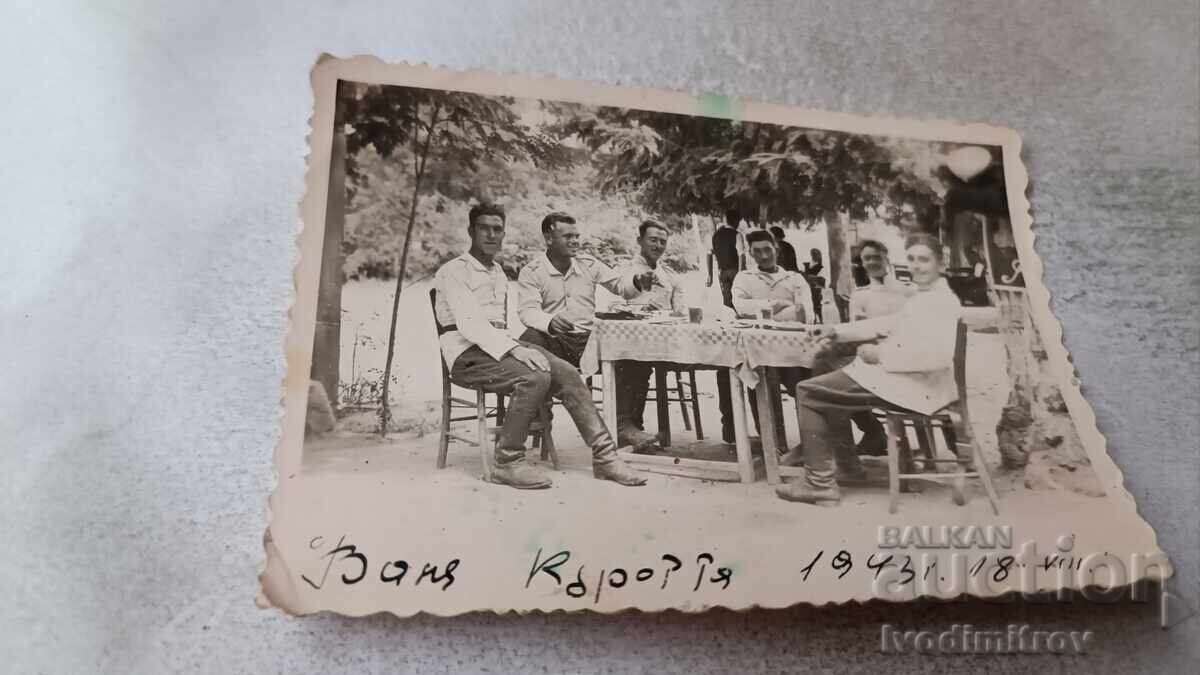 Photo: Men sitting around a table, having a drink