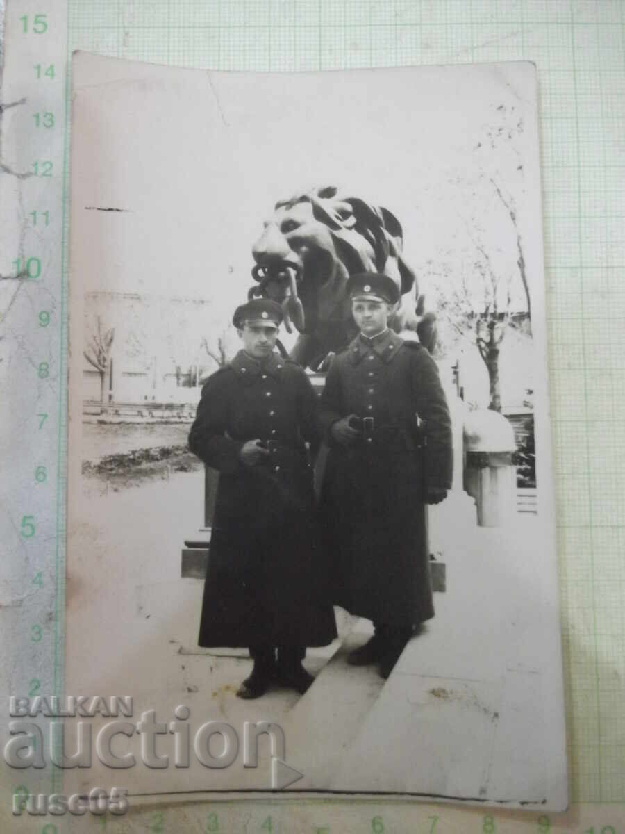Снимка на двама униформени пред лъва стара