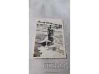 Photograph of a Young Man and Two Young Women on a Rock on the Seashore