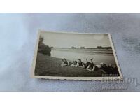 Φωτογραφία Νέων με ρετρό μαγιό ξαπλωμένοι δίπλα σε ποτάμι