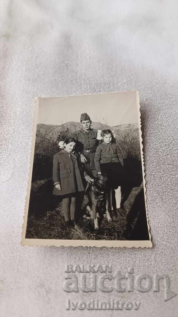Photograph of a Border Guard with a border guard dog and two girls Photograph of a Border Guard with a border guard dog and two girls