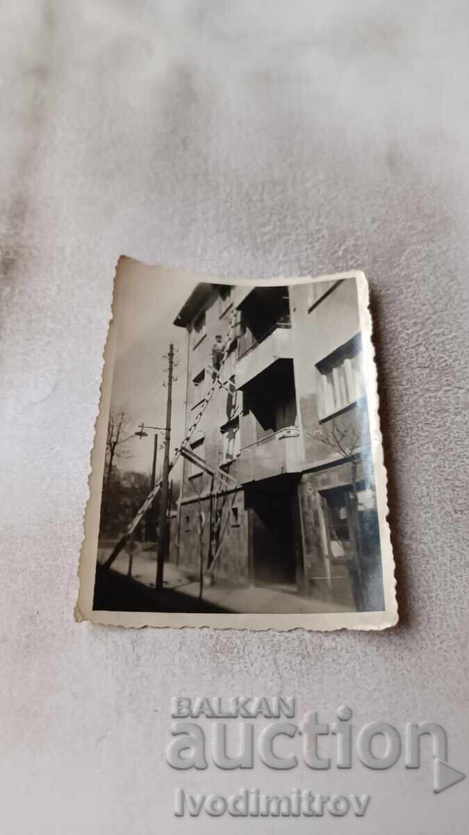 Fotografie Sofia Bărbat pe scară de lemn în fața unui bloc de locuințe Fotografie Sofia Bărbat pe scară de lemn în fața unui bloc de locuințe