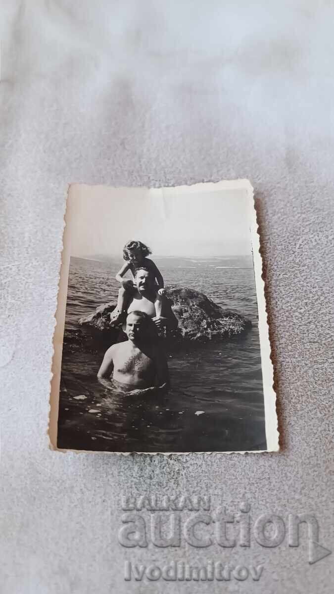 Photo of Two Men and a Little Girl on a Cliff by the Sea