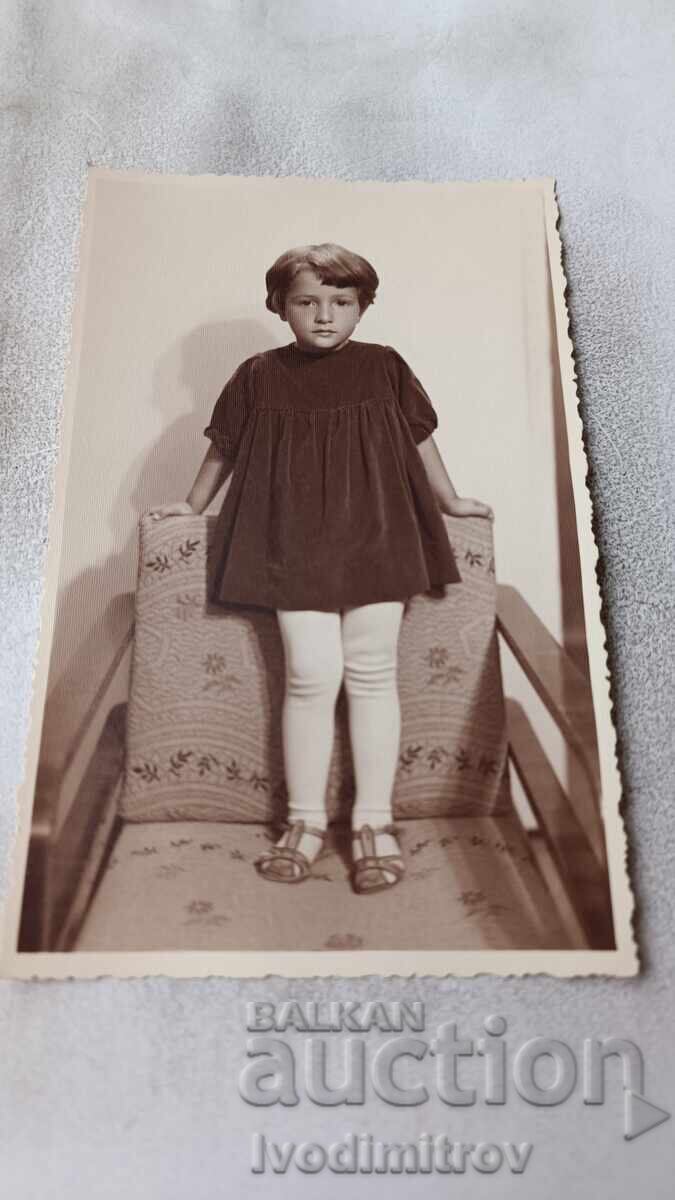 Photo A little girl sitting on a chair