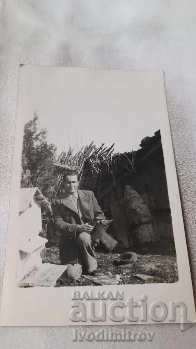Fotografie cu un bărbat lângă o stupină în curte Fotografie cu un bărbat lângă o stupină în curte