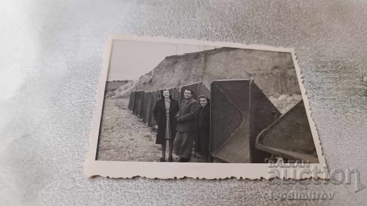 Photo: Man and two women in front of beach cabins Photo: Man and two women in front of beach cabins