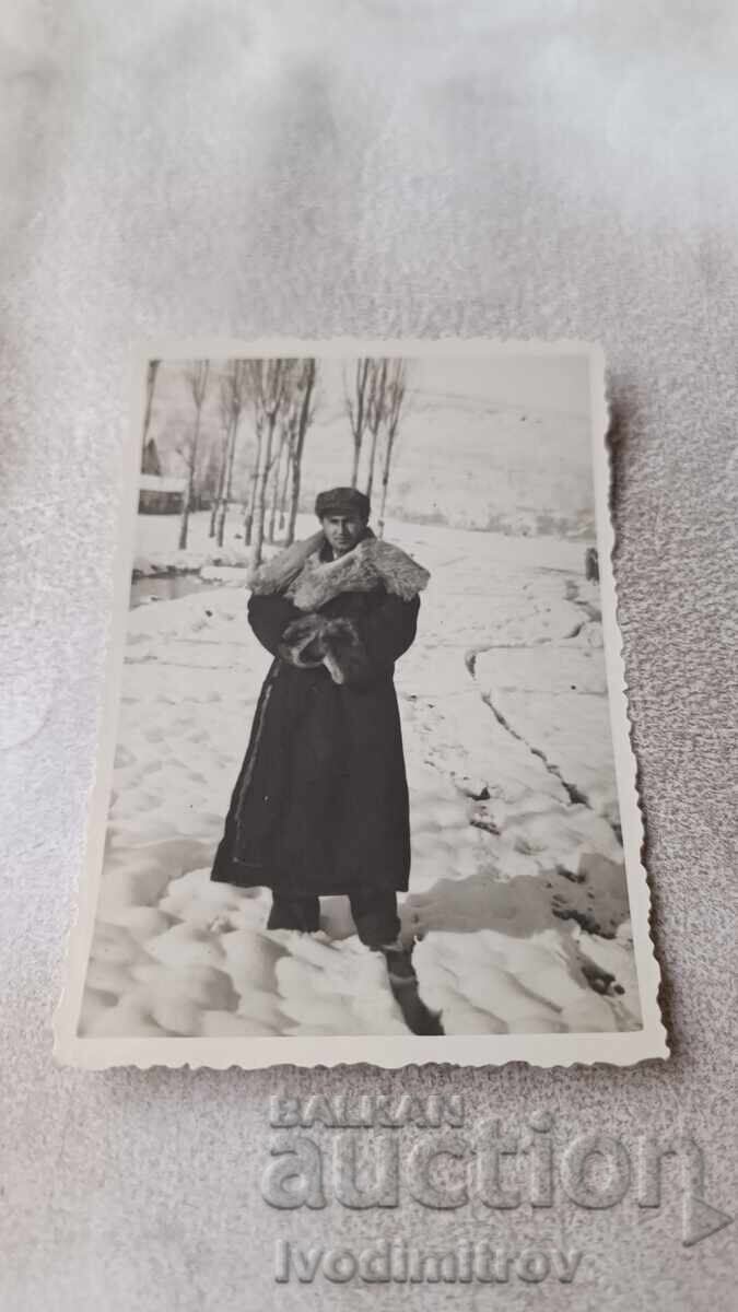 Photo of a man in a winter coat in the snow during winter