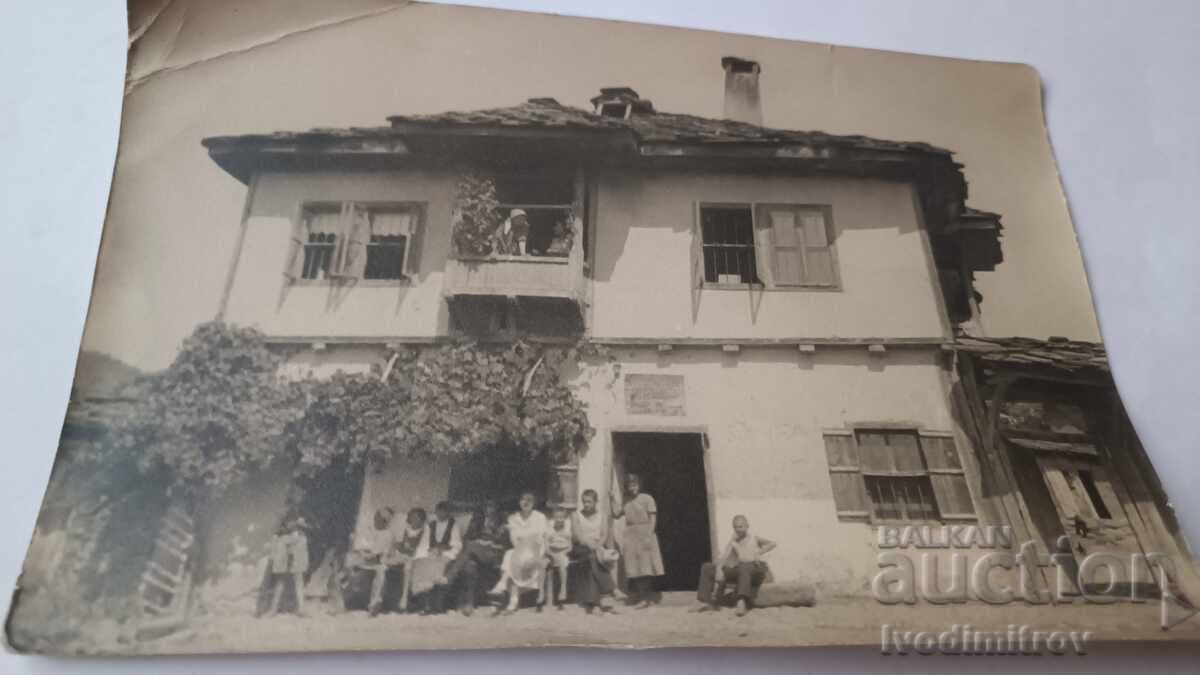 Fotografie Bărbați femei și copii în fața unei case țărănești vechi Fotografie Bărbați femei și copii în fața unei case țărănești vechi