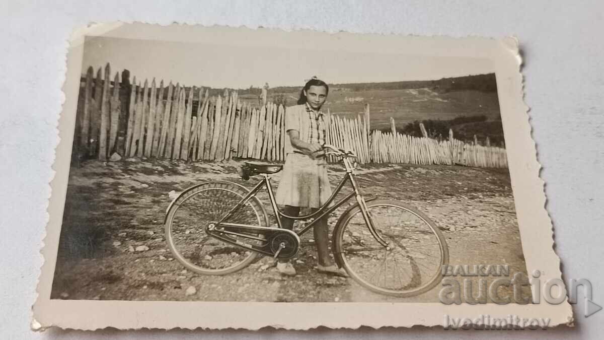 Photo of a young girl with a retro bicycle on the road