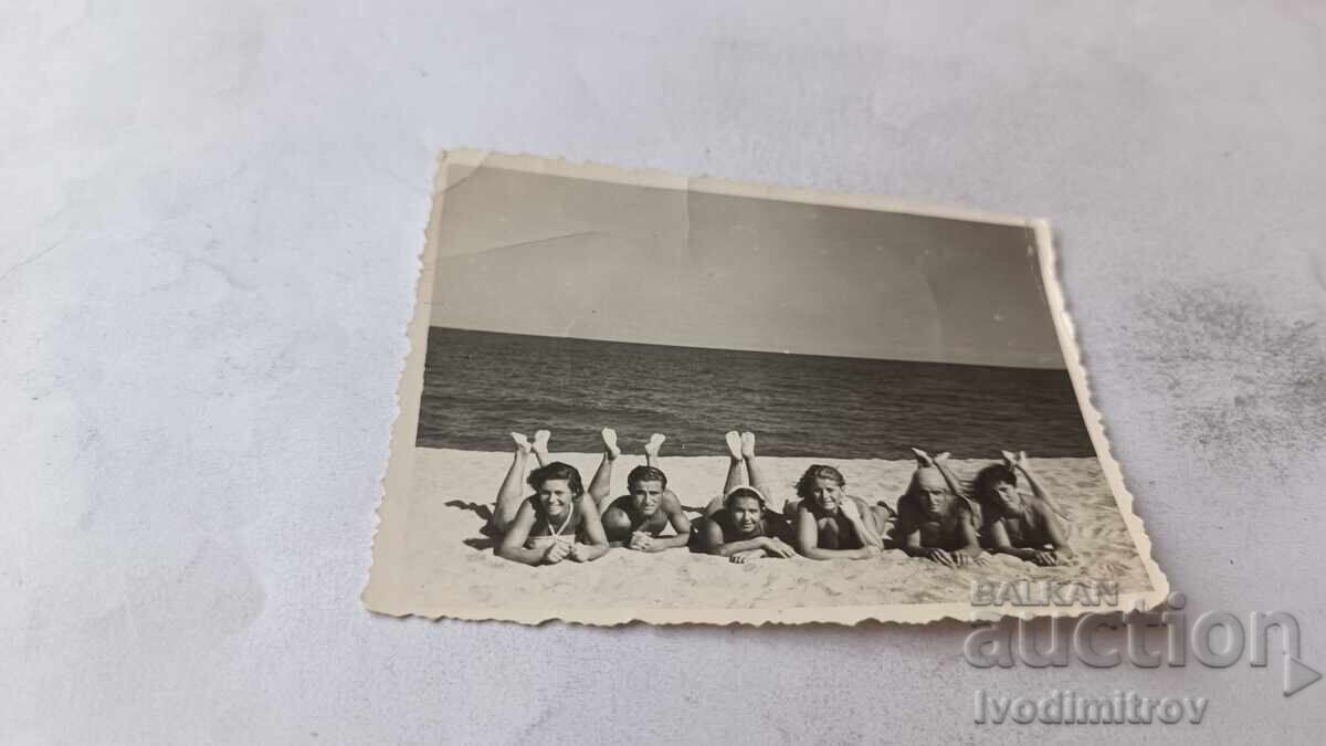 Fotografie Tineri și tinere întinse pe burtă pe plajă Fotografie Tineri și tinere întinse pe burtă pe plajă