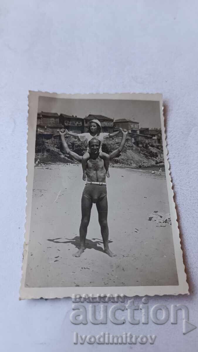 Fotografie Bărbat cu fetiță pe umeri pe plajă