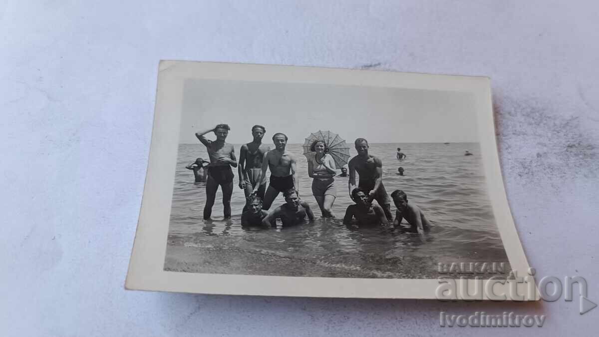 Fotografie Tineri și fată cu umbrelă pe mare