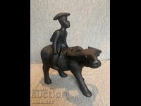 дървена фигурка на азиатски мъж, яздещ бивол