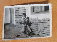 Copil pe bicicletă în fața unei case de țară