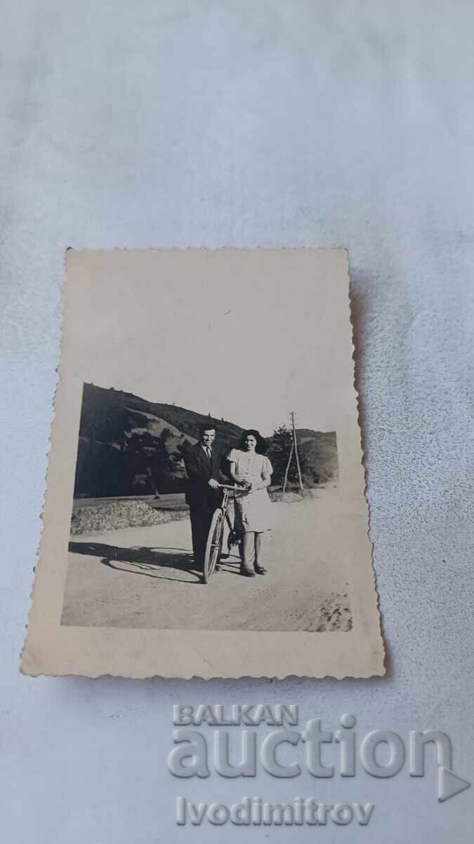 Photo: Young man and young woman with a retro bicycle on the road Photo: Young man and young woman with a retro bicycle on the road