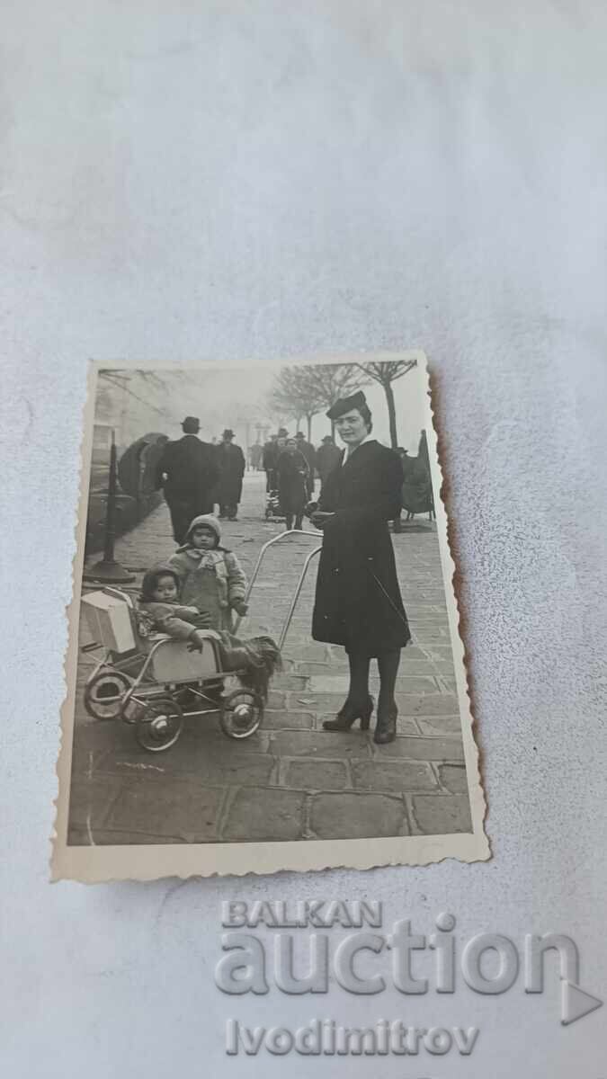 Fotografie Sofia Femeie și copii cu un cărucior retro pe trotuar Fotografie Sofia Femeie și copii cu un cărucior retro pe trotuar