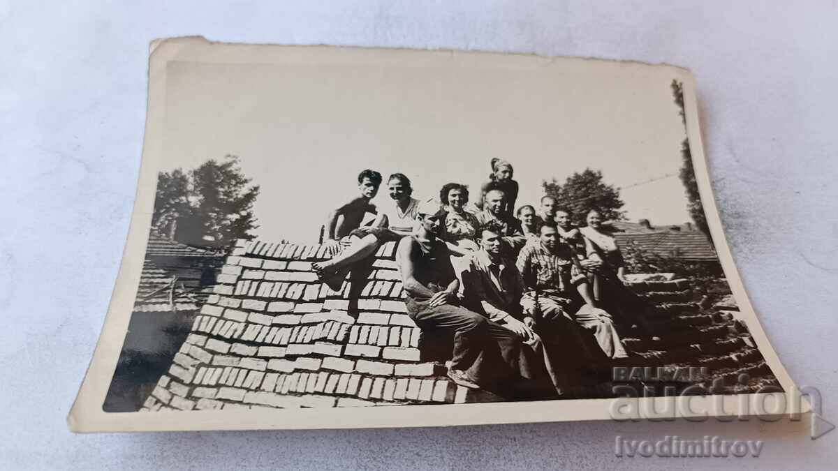 Photo: Young men and women on a pile of single bricks