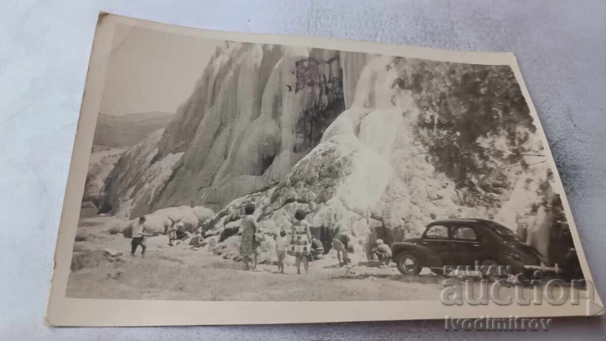 Fotografie bărbați, femei și copii lângă o cascadă înghețată