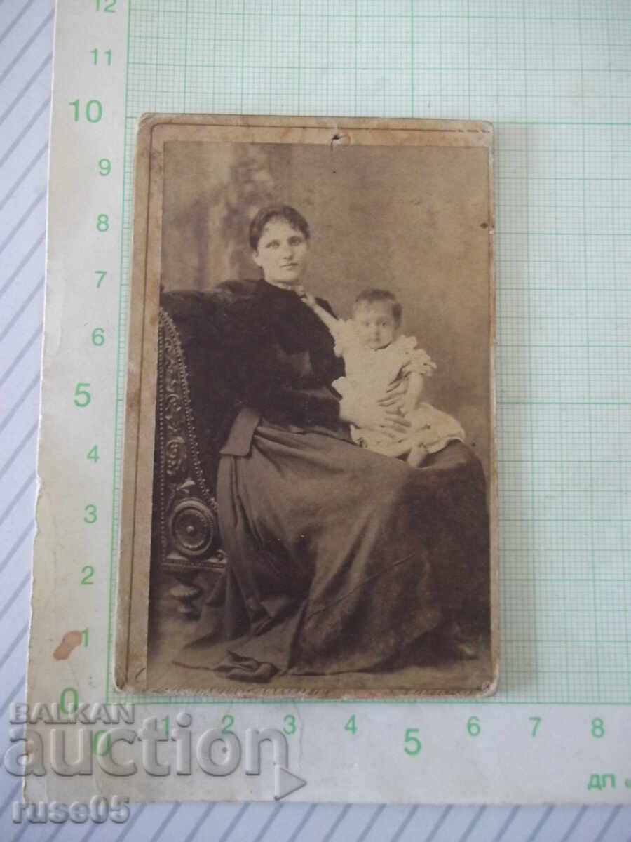 Old cardboard photograph of a mother with a child in a photo studio