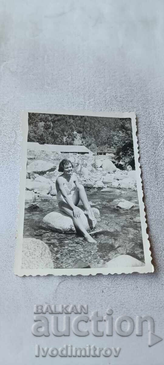 Fotografie Tânără fată stând pe o piatră lângă un râu