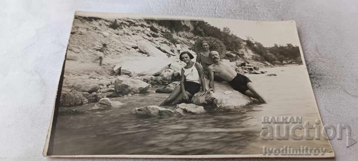 Fotografie bărbat, femeie și fată tânără pe o stâncă în mare