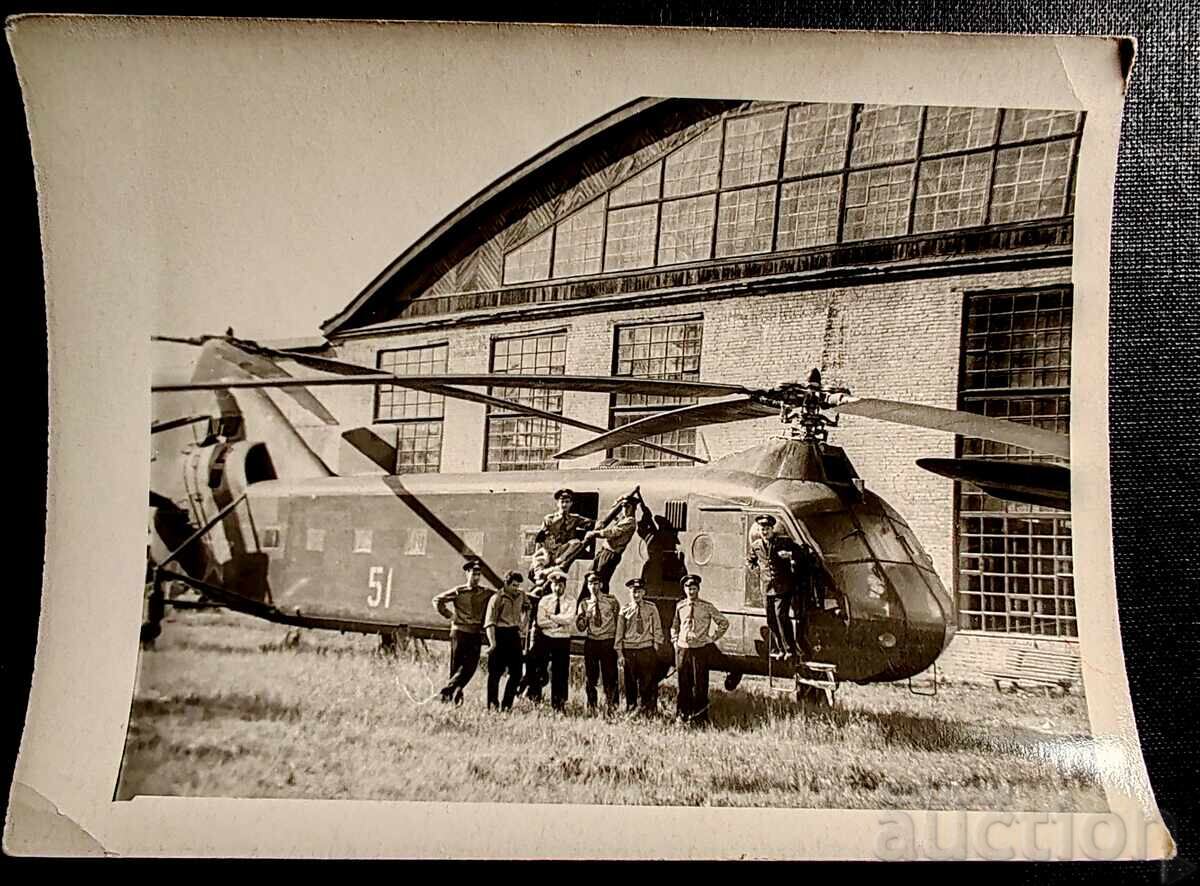 Această fotografie înfățișează un grup de militari în fața unui elicopter sovietic