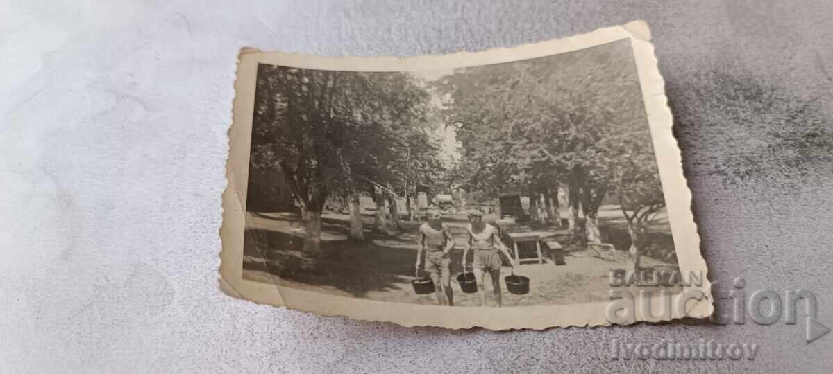 Fotografie: Bărbați care cară găleți pe o alee din parc