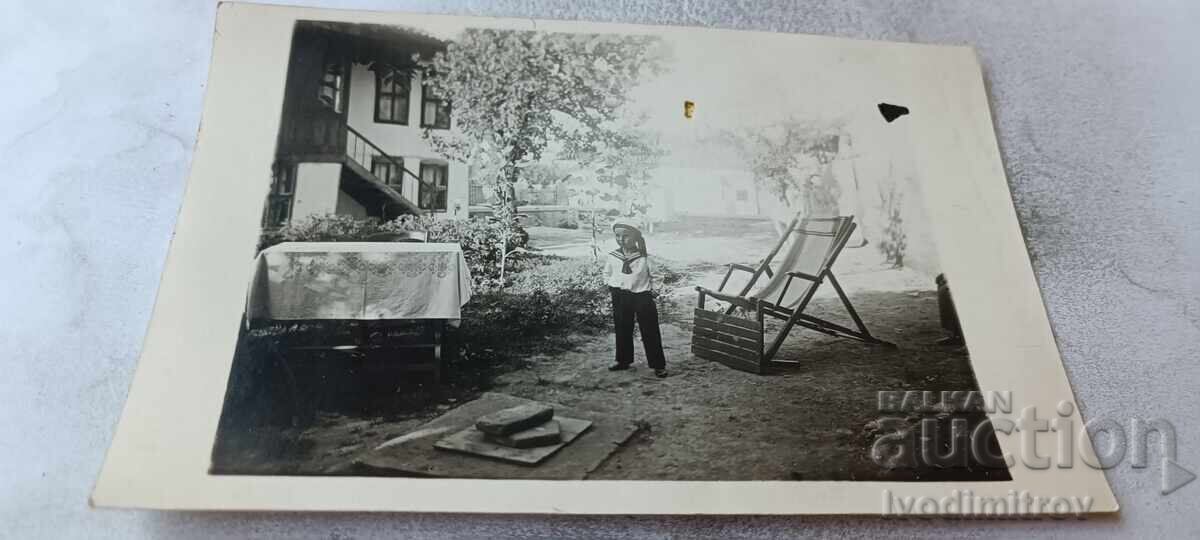 Fotografie băiețel cu tricou de marinar în curtea casei sale